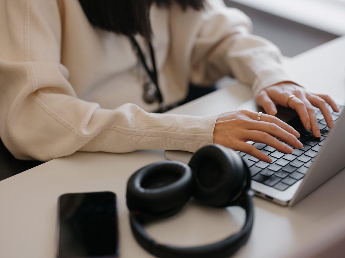 Team member working on laptop with headphones beside